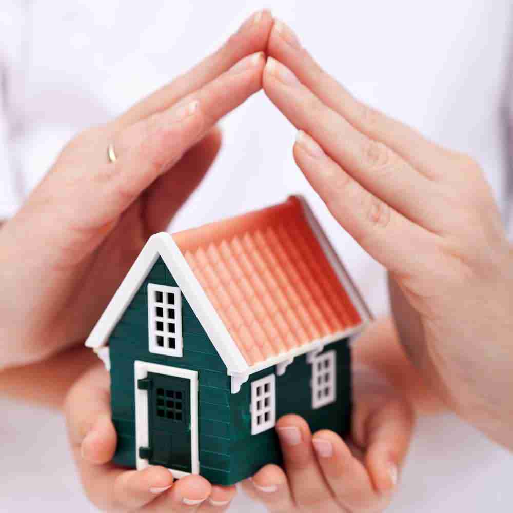 Hands protecting miniature house model.